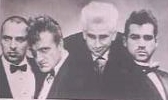 Four men in suits, LaPaglia appearing with bright white/blond hair.