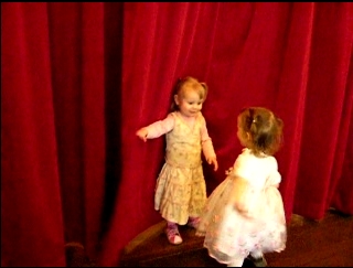 Little girls playing with red curtain