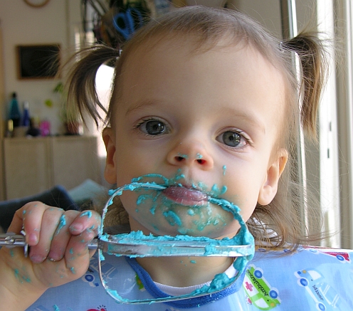 Toddler licking icing off of a beater